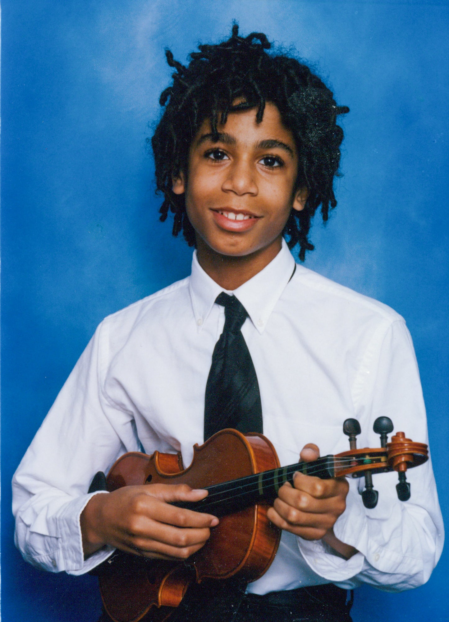 Brian Joseph's teenage-aged son Julian Joseph holding a violin against a blue background